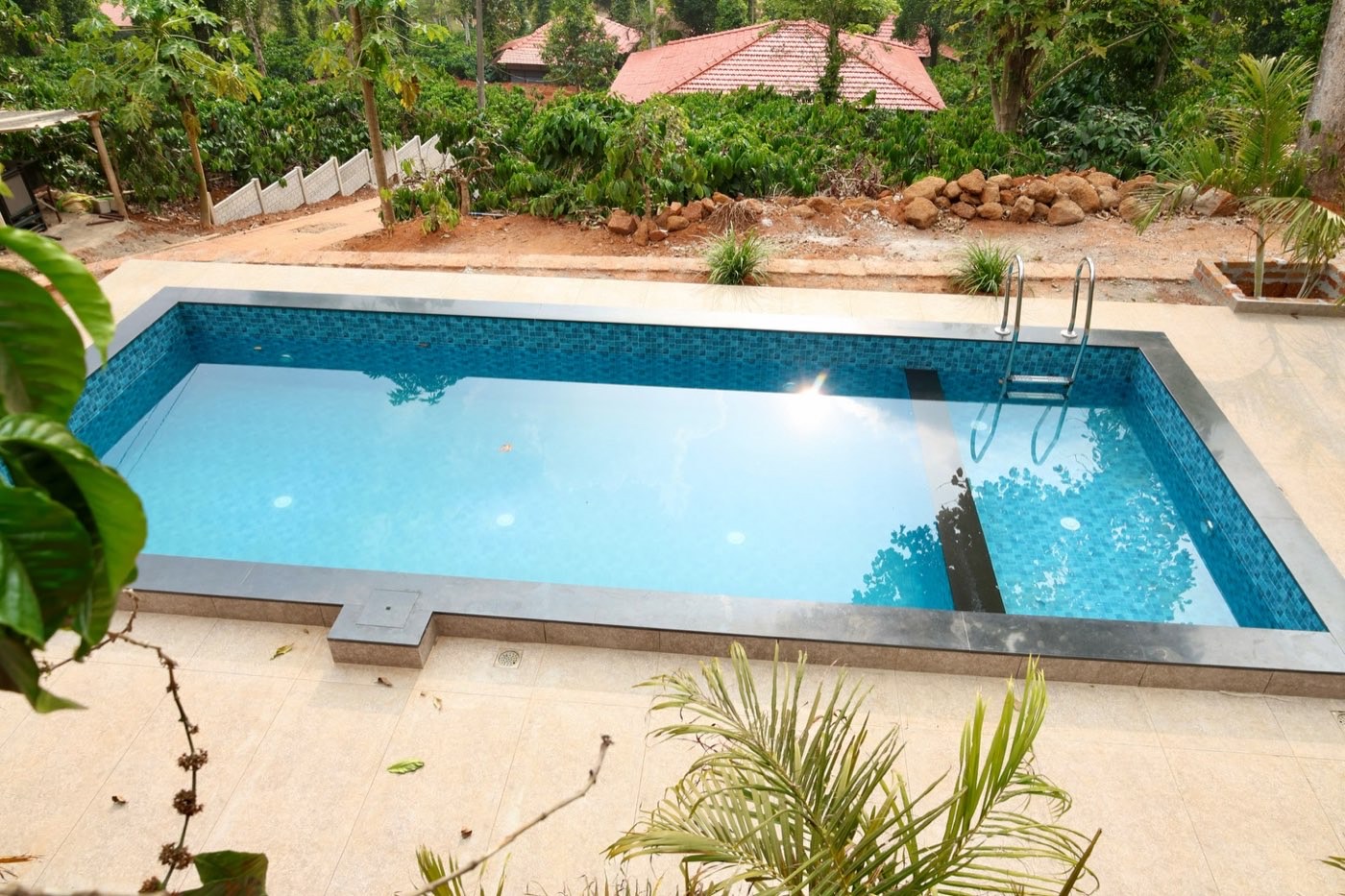 Outdoor swimming pool overlooking the coffee estate and cottage roofs
