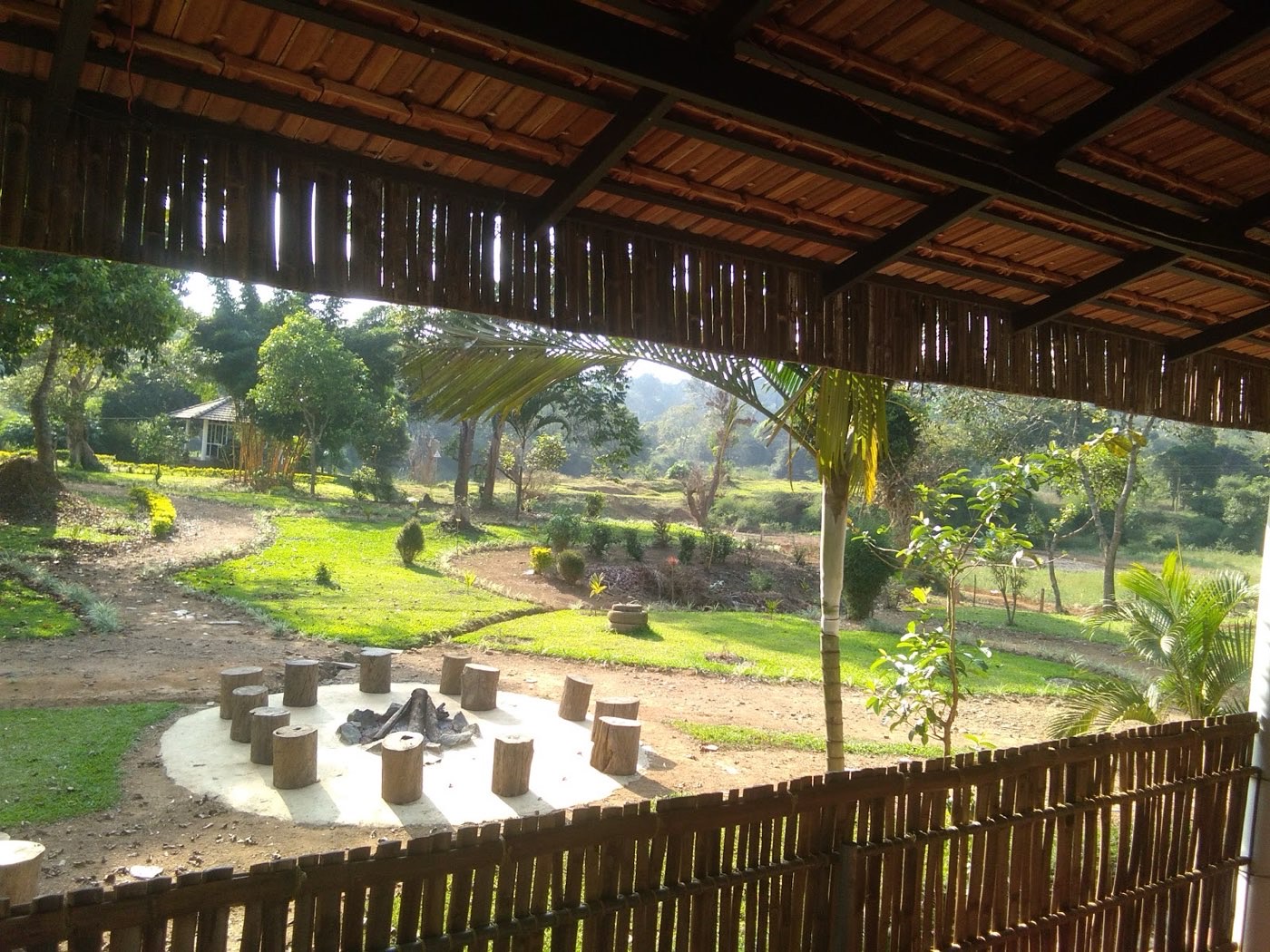 View of the lawns and fire pit from a thatched shelter